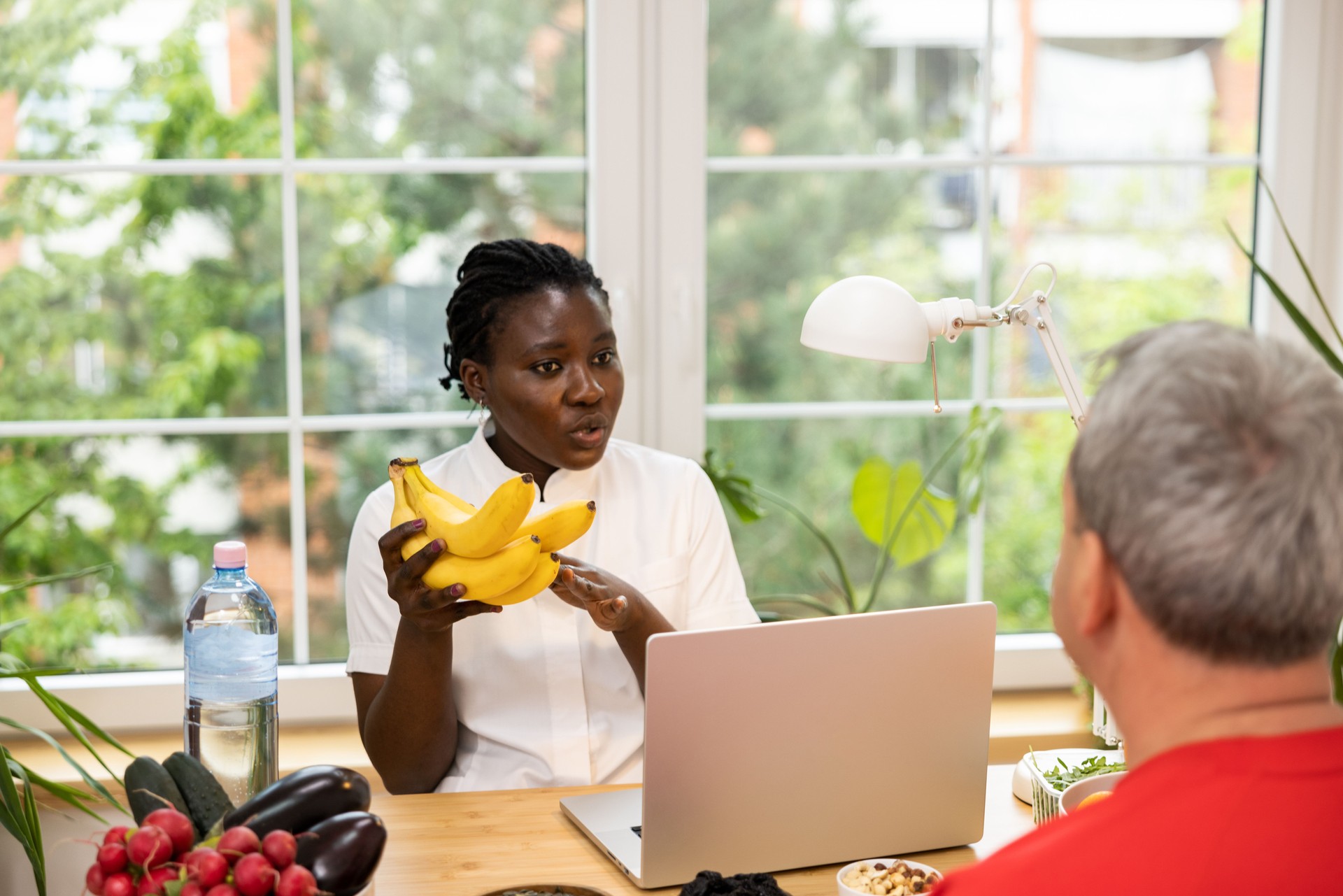 At her office, female nutritionist of Black ethnicity educating male client, about dieting during consultation